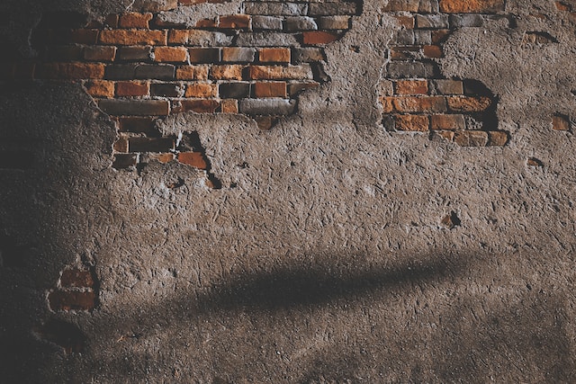 A patchy plastered wall with brick showing.